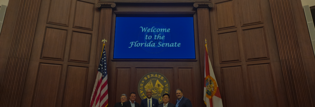 Bob Brillante and other members of legislature stand in front of a screen saying "Welcome to the Florida Senate"